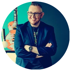 A man with glasses and a guitar in front of a blue background.